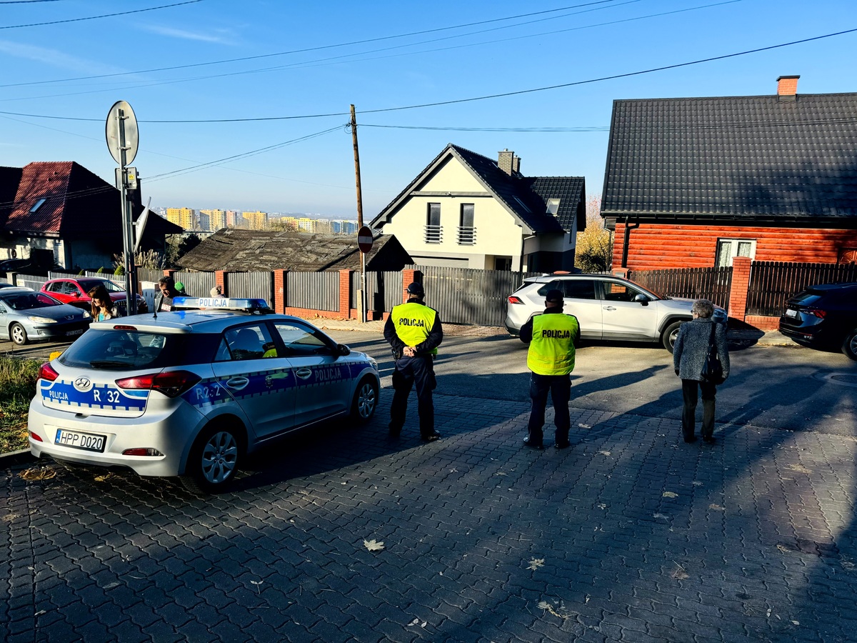 Umundurowani policjanci w odblaskowych kamizelkach kierujacy ruchem w okolicach cmentarza.