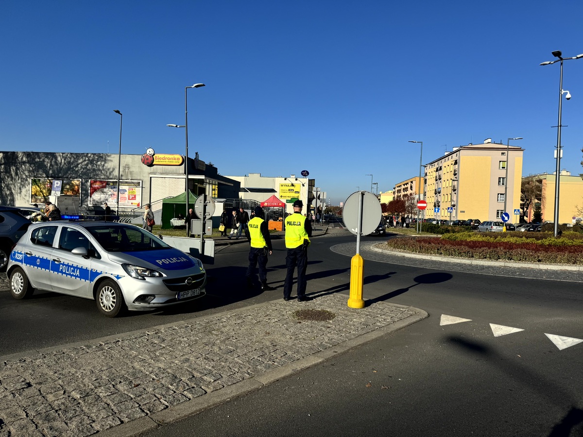 Umundurowani policjanci w odblaskowych kamizelkach kierujacy ruchem w okolicach cmentarza