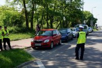 Policjant w obrębie jezdni instruuje stojących na chodniku kadetów