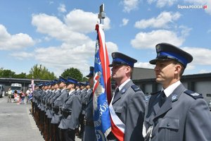 Stojący w szeregu policjanci. Na pierwszym planie poczet sztandarowy.