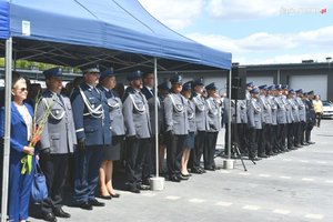 Policjanci i zaproszeni goście stojący w szeregu pod niebieskim namiotem.