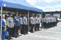 Policjanci i zaproszeni goście stojący w szeregu pod niebieskim namiotem.