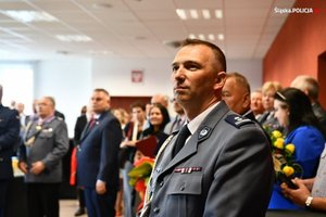 Przedstawiciele policji i zaproszeni goście oglądają prezentację multimedialną. Na pierwszym planie oficer policji.