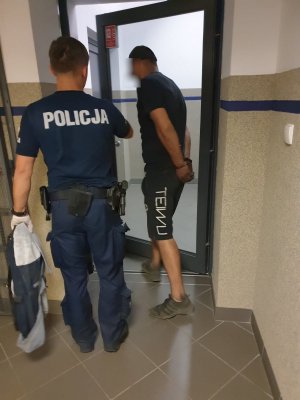 Umundurowany policjant prowadzący zatrzymanego mężczyznę