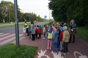 Policjant z dziećmi przechodzącymi przez przejście dla pieszych