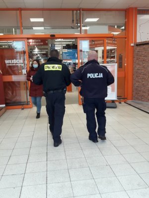 Umundurowany Policjant i Strażnik Miejski podczas wejścia do sklepu budowlanego.