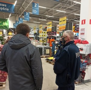 Umundurowany Policjant i Strażnik Miejski podczas legitymowania mężczyzny w sklepie budowlanym.