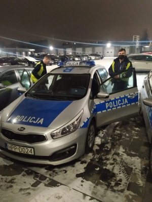 Umundurowani policjanci przy radiowozie oznakowanym w drodze do granicy Polski.