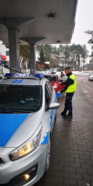 Umundurowani policjanci przy radiowozie oznakowanym w drodze do granicy Polski.