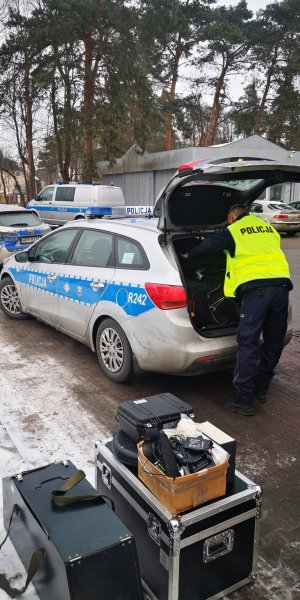 Umundurowani policjanci przy radiowozie oznakowanym w drodze do granicy Polski.