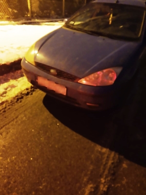 Samochód osobowy koloru niebieskiego stojący na poboczu ośnieżonej drogi.