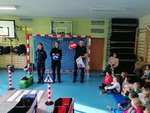 Umundurowani policjanci prowadzący prelekcje w Zespole Szkół Specjalnych nr 5 w Dąbrowie Górniczej z wykorzystaniem mobilnego miasteczka ruchu drogowego.