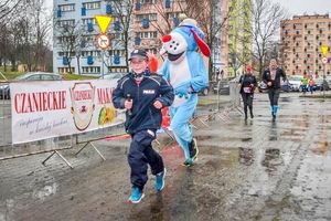 Biorący udział w biegu córka naszego kolegi przebrana w umundurowaniu policjanta i maskotka policyjna sznupek.