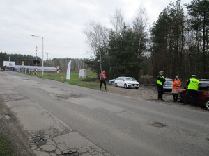 Umundurowani policjanci wraz z pracownikami Kolei Śląskich podczas działań na przejeździe kolejowym.