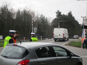 Umundurowani policjanci wraz z pracownikami Kolei Śląskich podczas działań na przejeździe kolejowym.