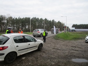 Umundurowani policjanci wraz z pracownikami Kolei Śląskich podczas działań na przejeździe kolejowym.