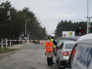 Umundurowani policjanci wraz z pracownikami Kolei Śląskich podczas działań na przejeździe kolejowym.