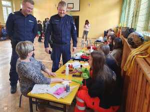 Umundurowani policjanci w trakcie szkolenia przeprowadzanego przez policjantów i kadetów klas mundurowych dla uczniów szkół podstawowych.