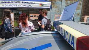 Umundurowani policjanci i sprzęt wykorzystywany w służbie, w trakcie Dąbrowskich Targów Pracy. Policjanci rozmawiający z potencjalnymi kandydatami.
