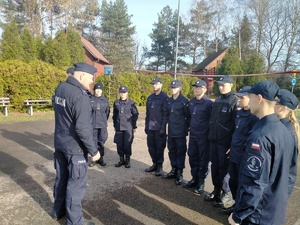 Umundurowani policjant prowadzący pogadankę z  kadetami klas o profilu mundurowym.