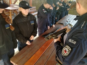 Umundurowany policjant omawia działanie jednostek broni palnej.