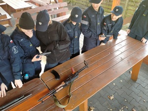 Umundurowany policjant omawia działanie jednostek broni palnej.