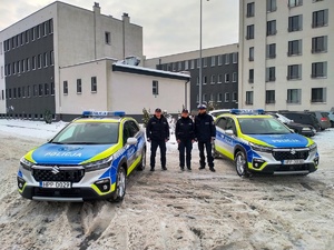 Umundurowani policjanci w nowych oznakowanych radiowozach.