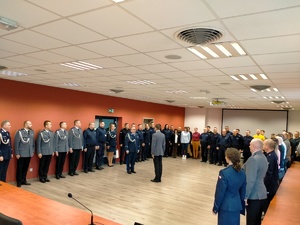 Umundurowani policjanci w trakcie uroczystości pożegnania emerytowanego funkcjonariusza.