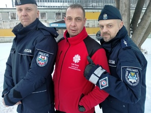 Umundurowani policjanci i ksiądz pozujący bokiem do zdjęcia.