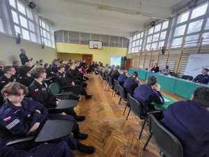 Umundurowani policjanci i uczniowie klas mundurowych podczas debaty. debata odbywa się w sali gimnastycznej szkoły średniej.