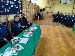 Umundurowani policjanci i uczniowie klas mundurowych podczas debaty. debata odbywa się w sali gimnastycznej szkoły średniej.