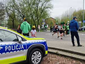 Na zdjęciu widać radiowóz policyjny oraz uczestników półmaratonu.