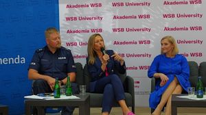 Na zdjęciu widzimy umundurowanego policjanta biorącego udział w konferencji.