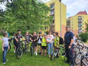 Na zdjęciu widać umundurowanego policjanta oraz uczniów którzy stoją  przy swoich rowerach.