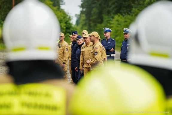 Na zdjęciu widzimy umundurowanych strażaków i policjantów oraz oznakowane radiowozy tych służb podczas działań na drodze ekspresowej.