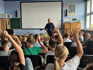 Umundurowany Policjant w trakcie pogadanek z dziećmi na półkoloniach.