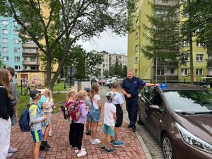 Umundurowany Policjant w trakcie pogadanek z dziećmi na półkoloniach.