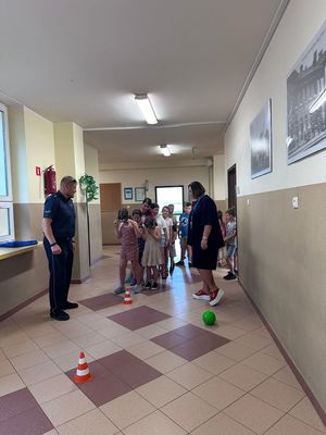 Na zdjęciu widzimy umundurowanego policjanta prowadzącego prelekcje w miejscach wypoczynku dzieci i młodzieży na trenie Dąbrowy Górniczej.