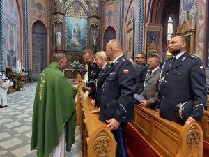 Na zdjęciu widzimy umundurowanych policjantów, księdza i ludzi uczestniczących w Mszy Świętej z okazji Święta Policji.