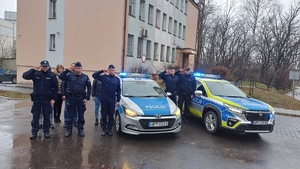 Umundurowani policjanci przy radiowozach oddajacy hołd zmarłemu koledze.