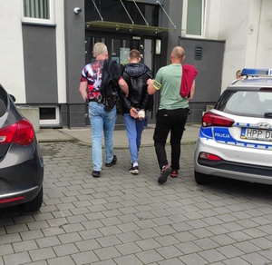 Zatrzymany prowadzony do komendy przez 2 nieumundurowanych policjantów.