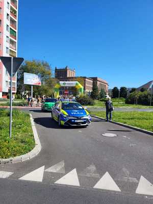 Umundurowani policjanci i oznakowane radiowozy podczas rajdu rowerowego ulicami Dąbrowy Górniczej