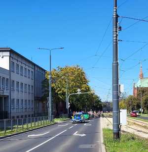 Umundurowani policjanci i oznakowane radiowozy podczas rajdu rowerowego ulicami Dąbrowy Górniczej