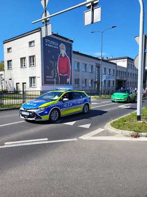Umundurowani policjanci i oznakowane radiowozy podczas rajdu rowerowego ulicami Dąbrowy Górniczej