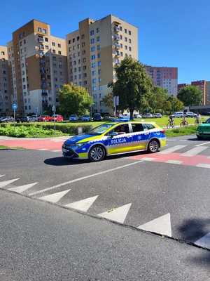 Umundurowani policjanci i oznakowane radiowozy podczas rajdu rowerowego ulicami Dąbrowy Górniczej