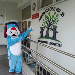 Umundurowani policjanci, radiowóz policyjny i maskotka Sznupek na festynie w przedszkolu.