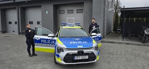 Widzimy policjantkę oraz policjanta stojących obok radiowozu.
