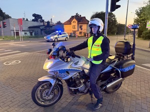 Zdjęcie przedstawia funkcjonariusza na policyjnym motocyklu podczas zabezpieczenia I Maratonu Zagłębiowskiego w dniu 23 maja 2026 roku.