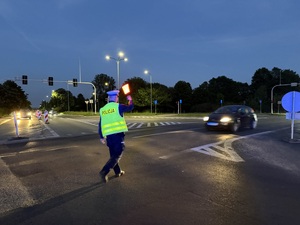 Zdjęcie przedstawia policjanta kierującego ruchem podczas zabezpieczenia I Maratonu Zagłębiowskiego w dniu 23 maja 2026 roku.