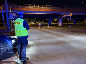 Zdjęcie przedstawia umundurowanego policjanta stojącego tyłem podczas zabezpieczenia I Maratonu Zagłębiowskiego w dniu 23 maja 2026 roku.